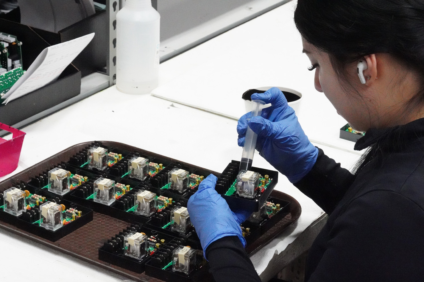 Woman using syringe to fill shell for potting PCB boards